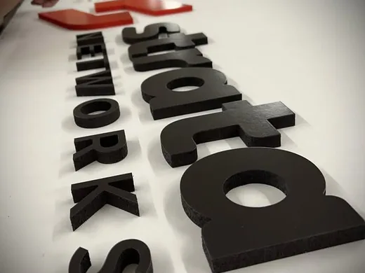 Black dimensional letters with red logo components laid out for alignment