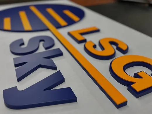 Blue and orange dimensional letters arranged on a white sign face