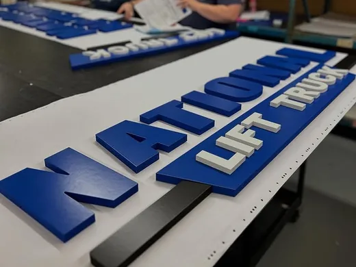 Blue and white dimensional letter set being arranged during shop production