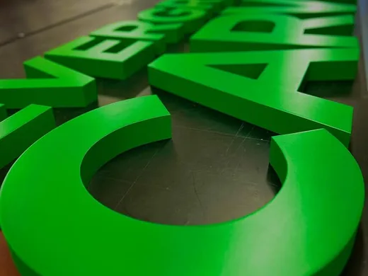Bright green dimensional letters arranged on a shop production table