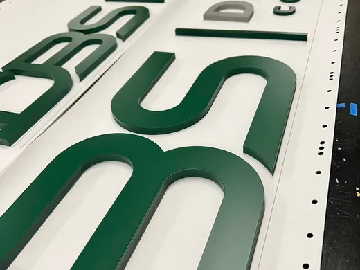 Green and silver dimensional business letters arranged on a large sign panel