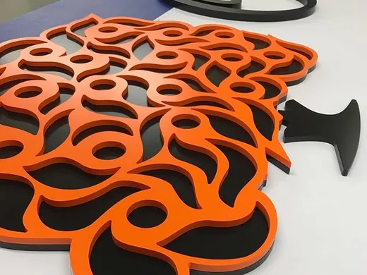Orange and black layered tiger logo components arranged on a production table