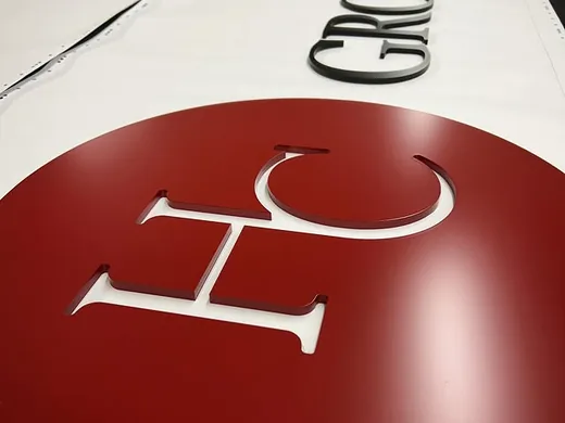 Red circular logo face and black dimensional letters arranged during sign production