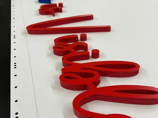 Red script dimensional letters arranged in order on a production table