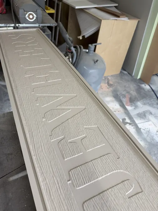 Close view of a routed sign panel border and woodgrain field before painting