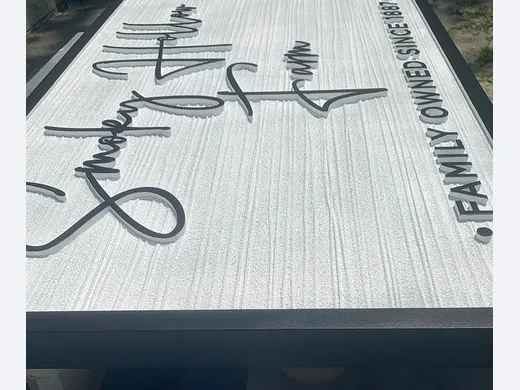 Script dimensional lettering and logo pieces arranged on a textured sign face during production