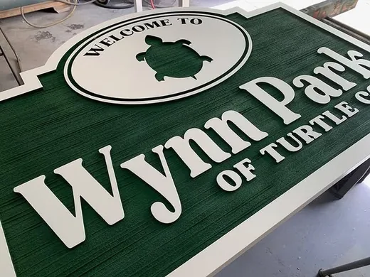 Wynn Park green and white dimensional community sign with turtle logo and woodgrain texture