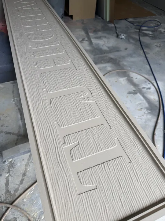 Long routed woodgrain sign panel shown before painting